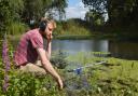 PhD student Jack Greenhalgh listening to the sounds of underwater wildlife in a restored pond at Swanton Morley Farms