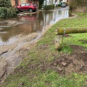 Homes on Neatherd Moor in Dereham, protected by sandbags from the floodwater emanating out of the pond - pictured hours before the repair was made on Wednesday morning.